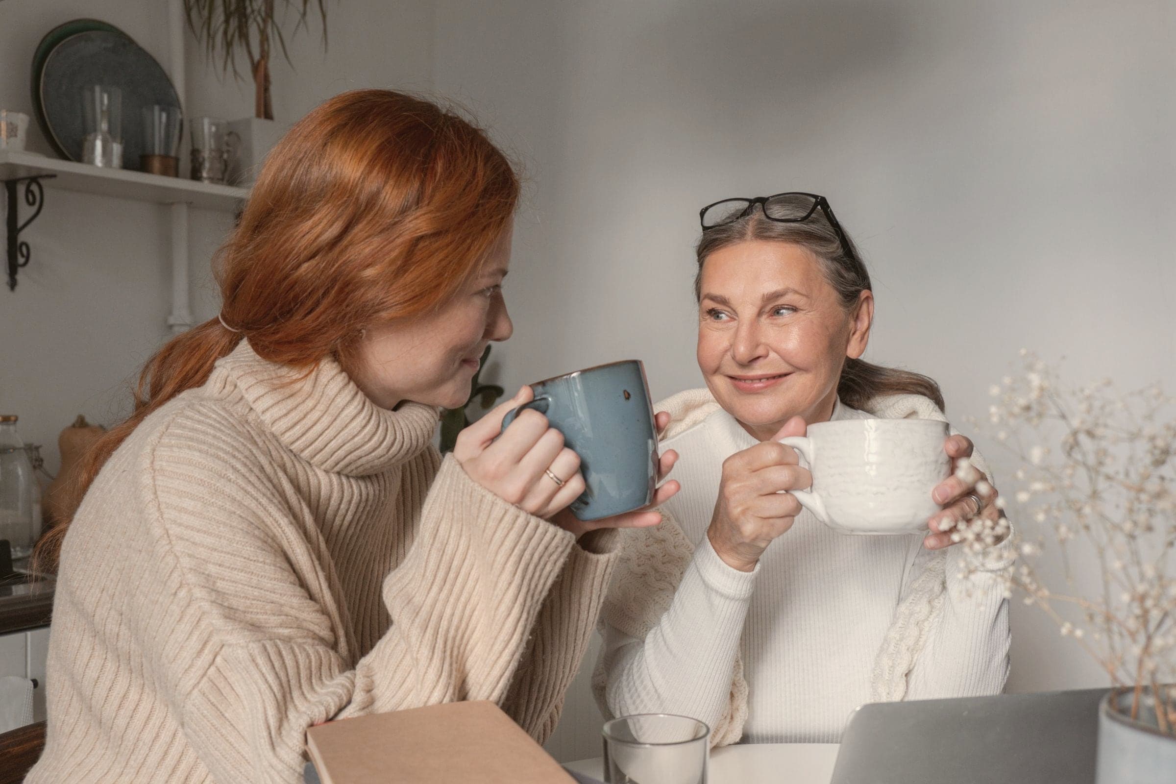 Une femme et sa mère prennent le thé ensemble à la maison et se sourient.